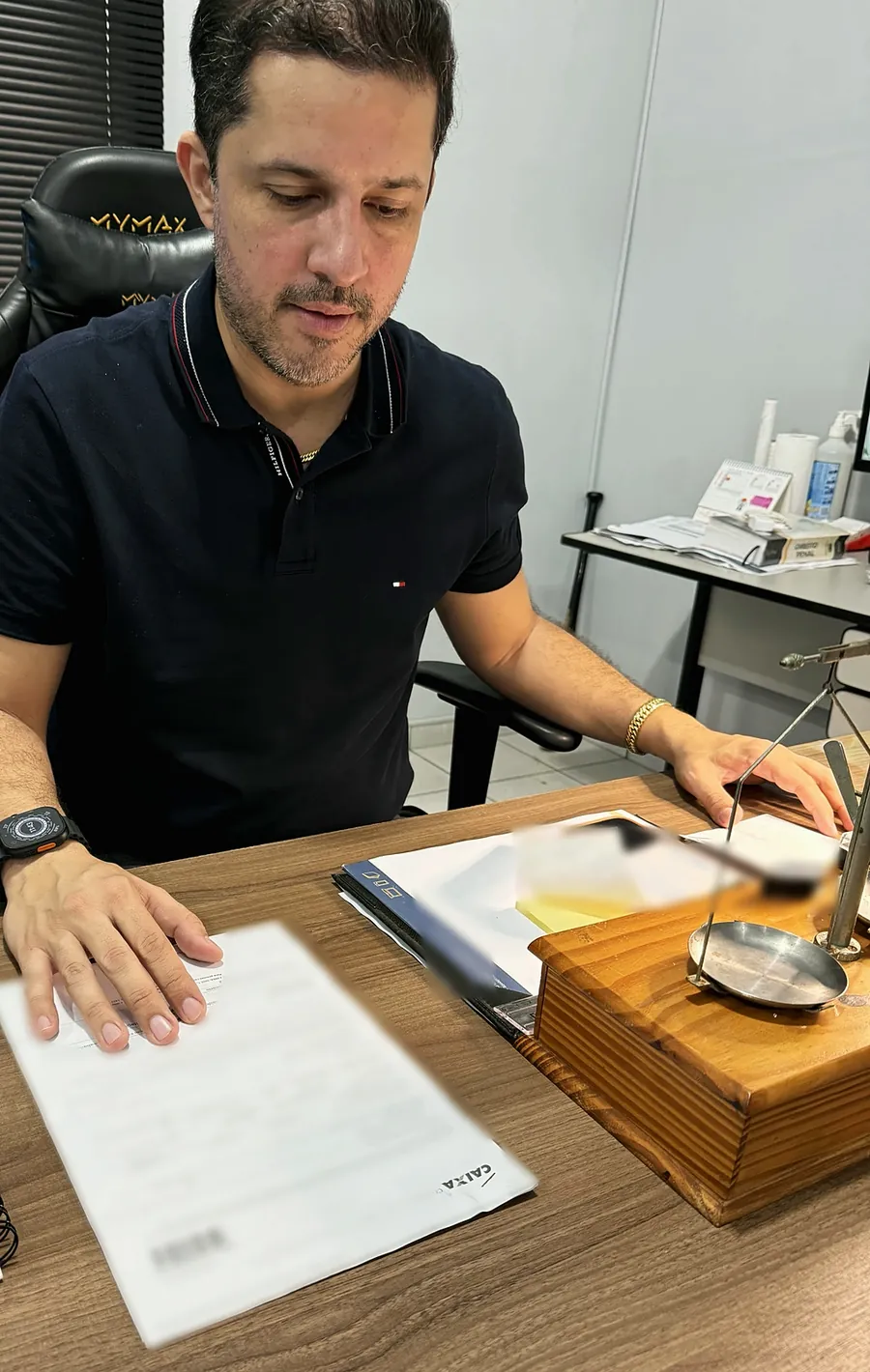 Avaliador da TH Joias com um contrato de penhor da Caixa sobre a mesa, dados do cliente ocultos