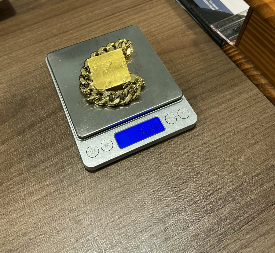 Pulseira e barrinha de ouro na balança de precisão, na mesa de avaliação da TH Joias