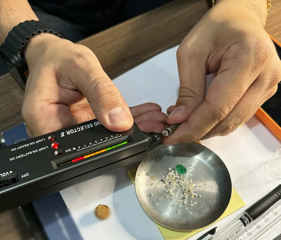 Testador de diamante sobre bandeja com diamantes e uma esmeralda, na TH Joias